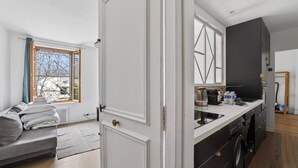 Una cocina moderna con lavadora integrada, un comedor con sofá y un amplio ventanal con vistas al exterior.