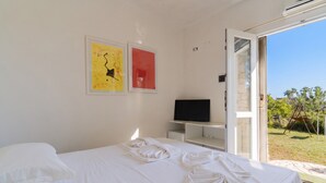 Quarto com cama, televisão e obras de arte na parede.
