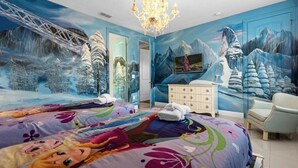 Et soveværelse med et mural af et sneklædt bjerglandskab, en lysekrone, en seng med farverigt sengetøj, en kommode og en stol.