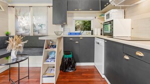 A modern kitchen with dark cabinets, a white countertop, and a microwave. - “3-Bedroom Mobile Home in St Aygulf” with Shared Pool, Wi-Fi, and Air Conditioning (Fréjus)