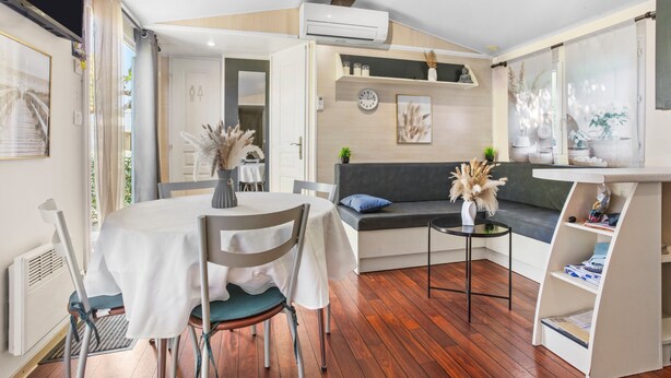 A modern living room with a dining table, chairs, a sofa, and a small side table. - “3-Bedroom Mobile Home in St Aygulf” with Shared Pool, Wi-Fi, and Air Conditioning (Fréjus)