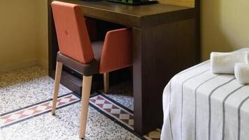 Une chambre d’hôtel équipée d’un bureau, d’une chaise, d’un lit et d’un téléviseur fixé au mur.