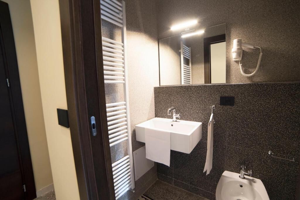 A modern bathroom with a white sink, a mirror, and a bidet.
