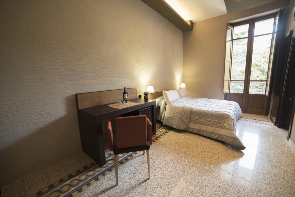 Une chambre à coucher avec un lit, un bureau, une chaise et une fenêtre.