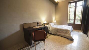 Une chambre à coucher avec un lit, un bureau, une chaise et une fenêtre.