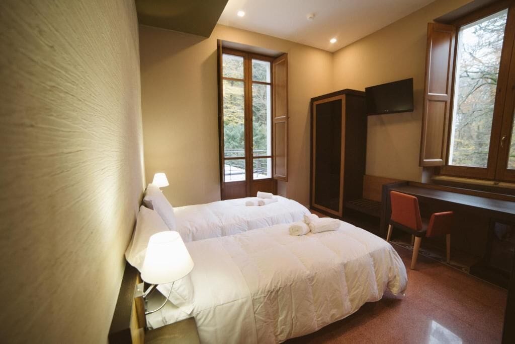 A bedroom with a bed, a desk, a chair, and a TV.