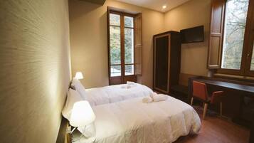 A bedroom with a bed, a desk, a chair, and a TV.