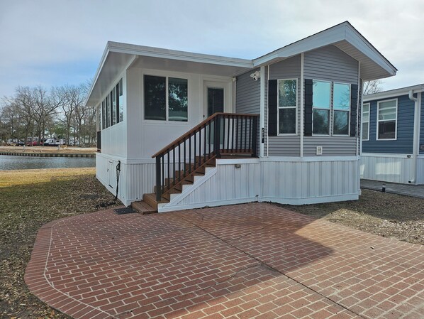 A two-story house with a front porch, a staircase, and a brick patio.