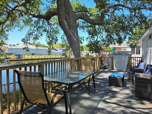 Une terrasse avec une table et des chaises, donnant sur un plan d’eau et une marina.