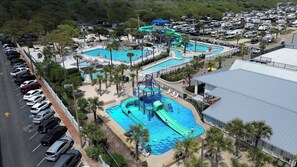 Un parc aquatique doté de plusieurs piscines, de toboggans et d’un parking rempli de camping-cars.
