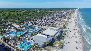 A coastal resort with multiple swimming pools, beach access, and a large RV parking area.