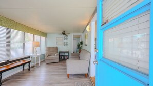 A living room with a blue door, a ceiling fan, a bench, and a sofa.