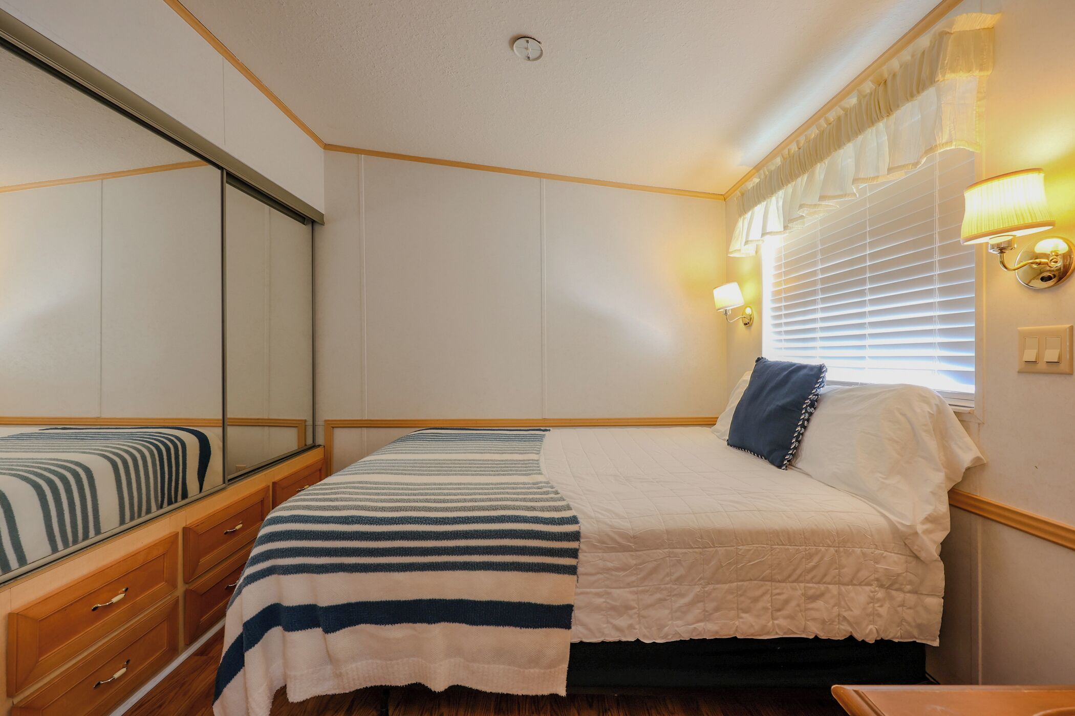 Ein Schlafzimmer mit einem Bett, einem Schminktisch, einem Spiegel und Wandleuchten.