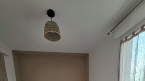 Ett sovrum med en stor säng, en hängande lampa och ett fönster med gardiner.