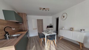 Ett modernt kök med en bänkskiva i trä, en inbyggd diskho och en matplats med ett vitt bord och svarta stolar.
