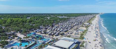 A coastal resort with multiple swimming pools, beach access, and a large RV parking area.