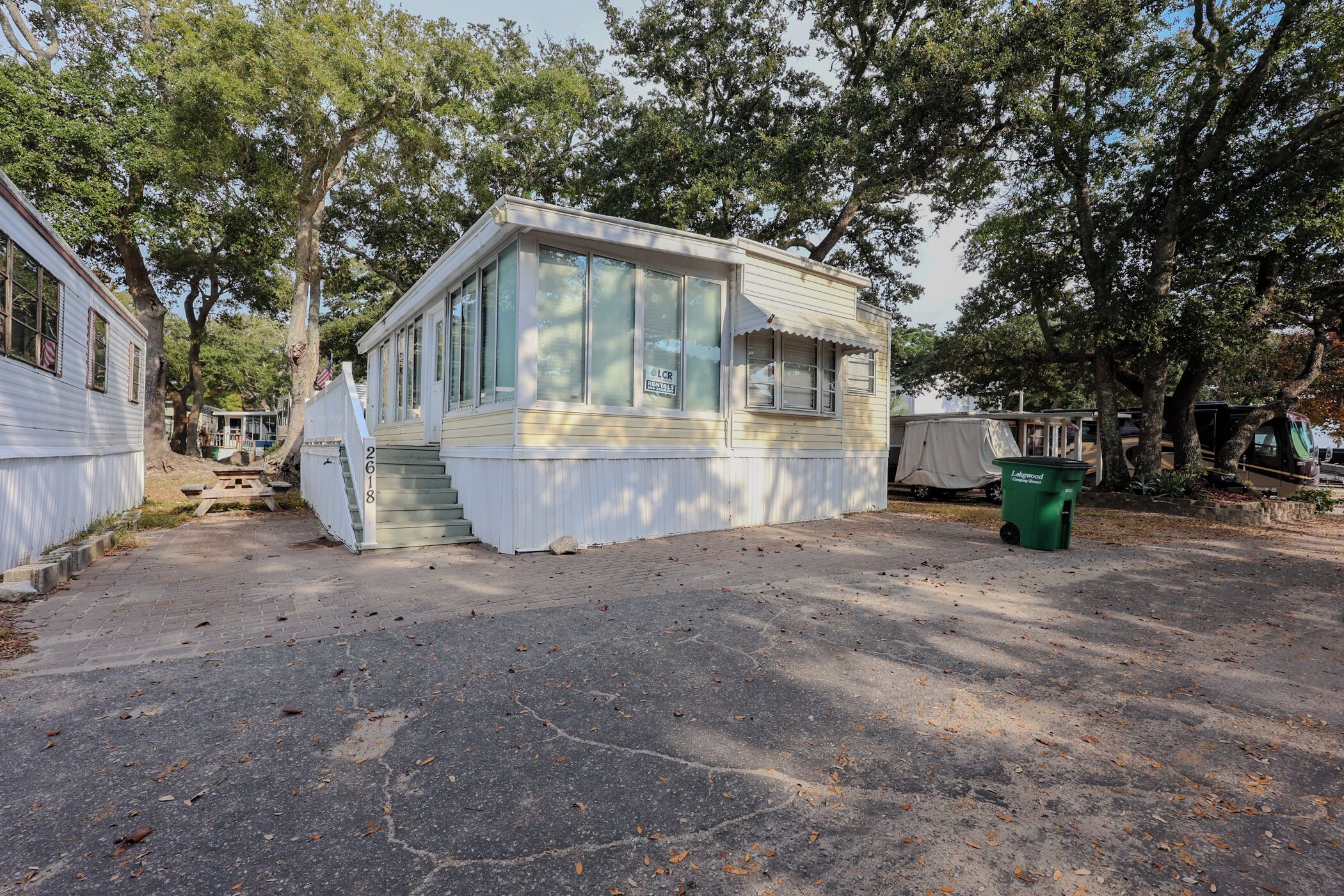 A small, single-story mobile home with a front porch and a covered patio area.