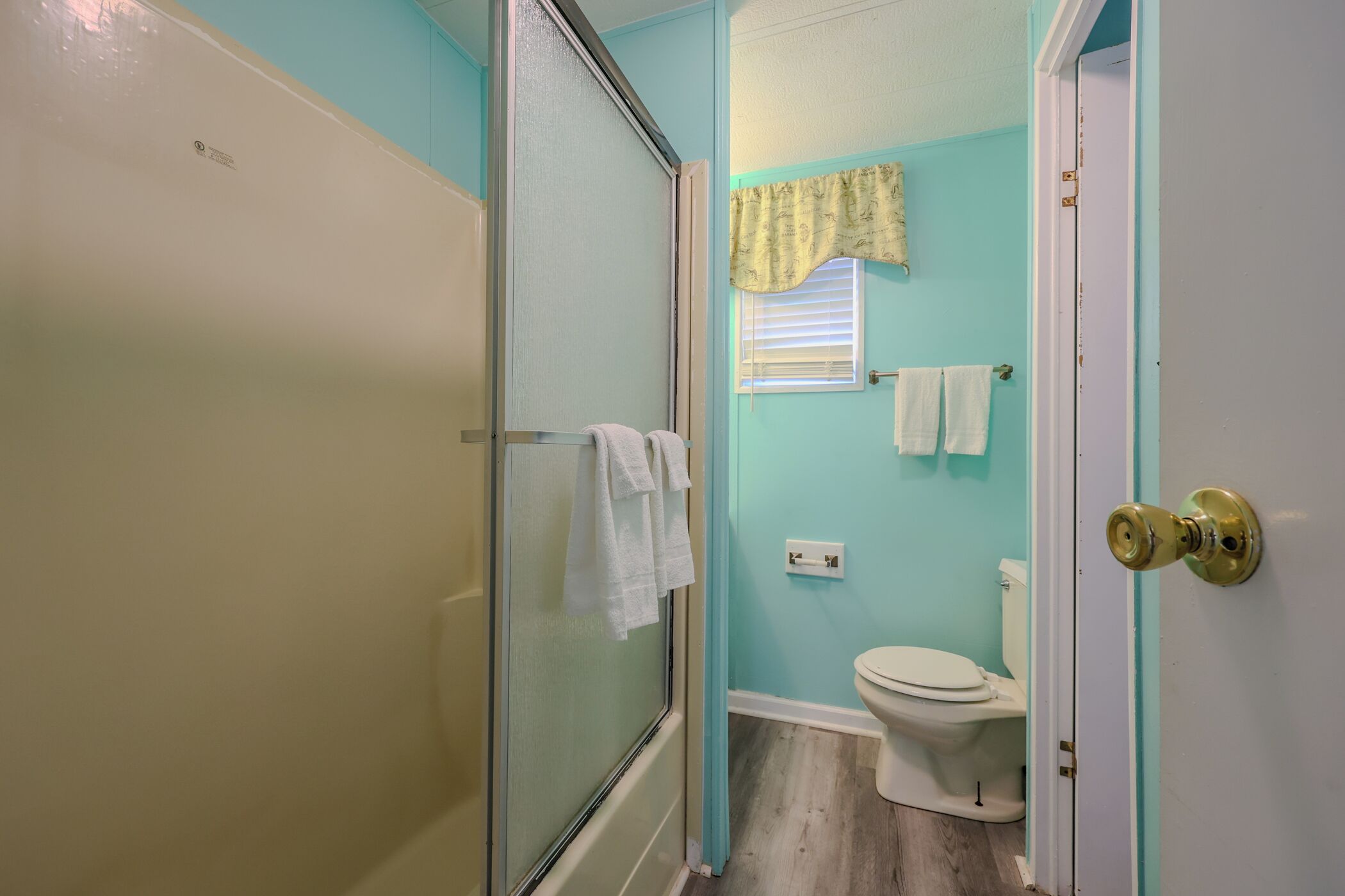 Baño con ducha, inodoro y perchero para toallas.