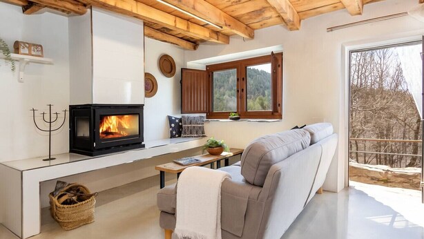A modern living room with a wood-burning stove, a sofa, and a view of the outdoors. - Relax Nature |8 P | BBQ | Wi-Fi | Pool | Foosball (Molló)