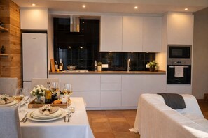 A modern kitchen with white cabinetry, a built-in oven, and a dining area set with white linens and a table set for two. - Adults Only Rural | 2 P | Pool | WiFi| BBQ| Girona (Madremanya)