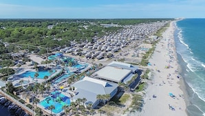 A coastal resort with multiple swimming pools, beach access, and a large RV parking area.