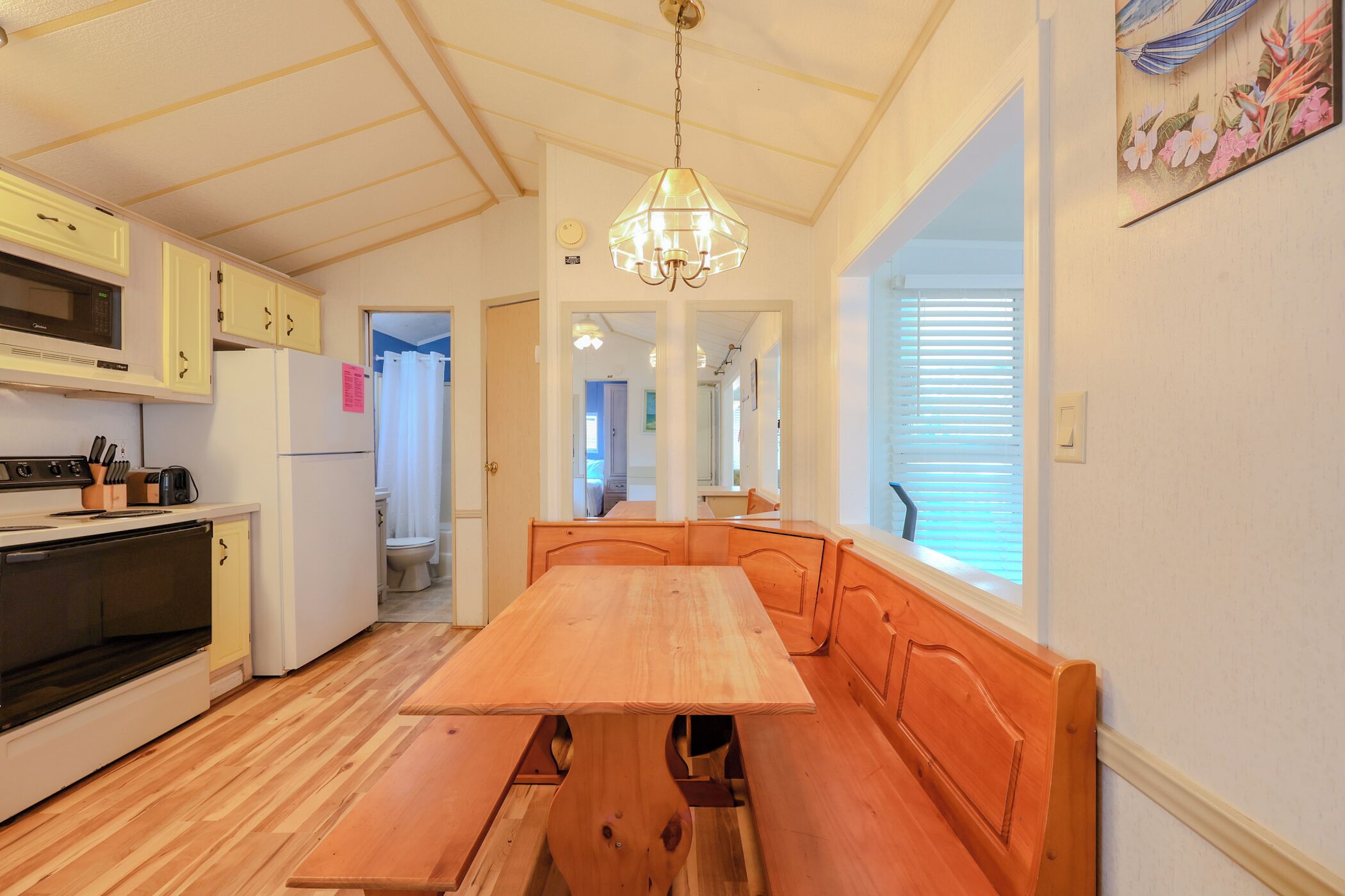 Une cuisine avec des meubles de rangement en bois, un four encastré et une table à manger avec des bancs.