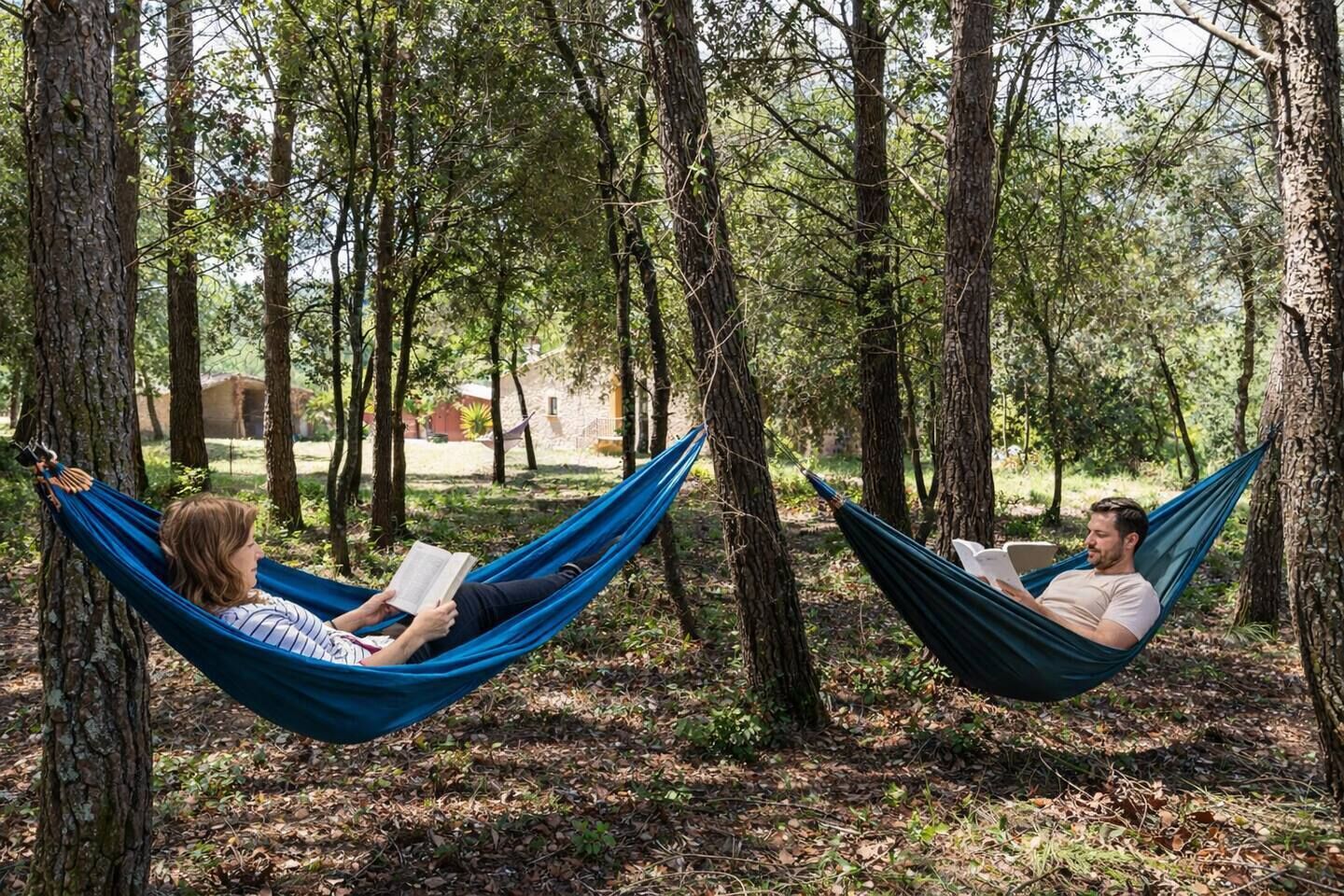 Dos personas descansando en hamacas en un área boscosa.