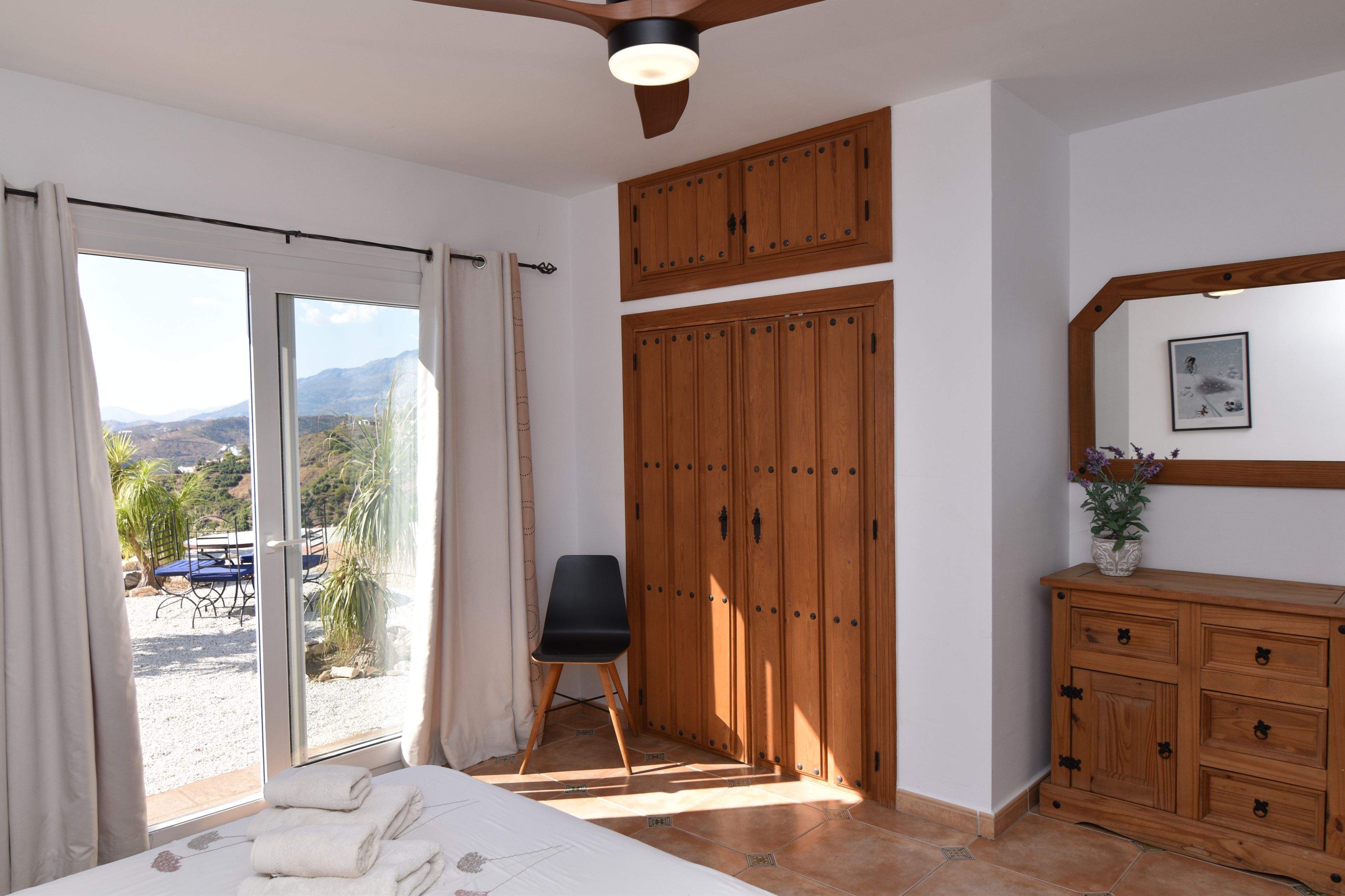 Ein Schlafzimmer mit Bett, Stuhl, Kleiderschrank und Blick ins Freie.