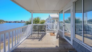 Um deck coberto com vista para um lago, corrimãos brancos e um banco.