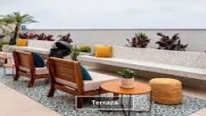 Een terras met houten stoelen, een kleine ronde tafel en plantenpotten.