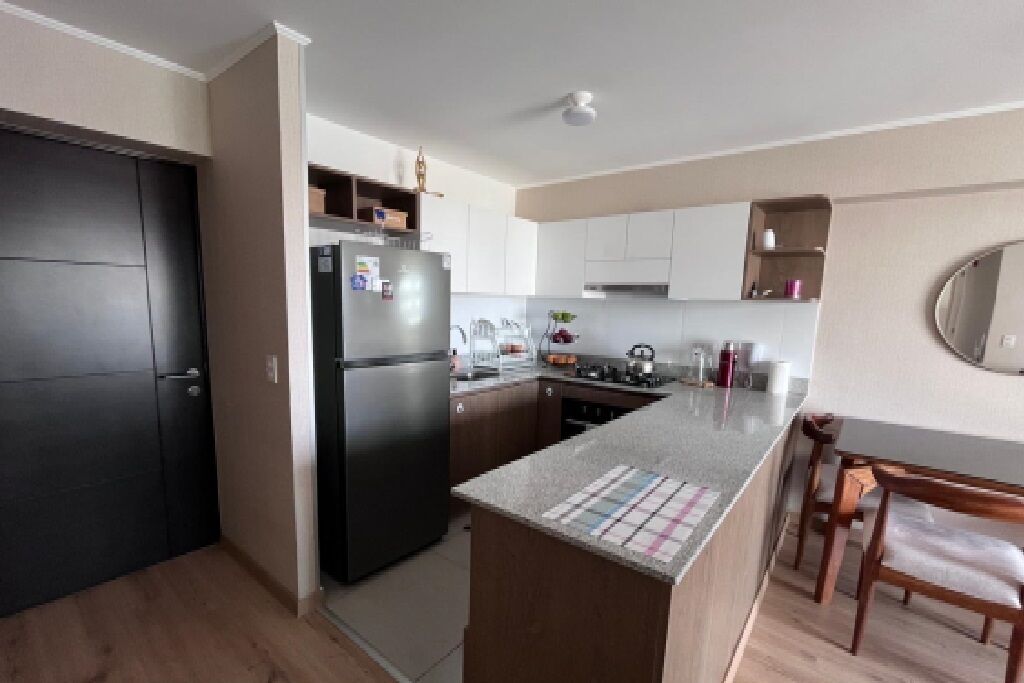 A compact kitchen with a refrigerator, stove, and sink. There is a dining area with a table and chairs.
