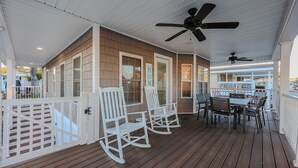 A covered porch with rocking chairs, a table, and chairs, and a ceiling fan. - 8143 Seascape Deluxe- Sleeps 8 (Myrtle Beach)