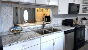 A kitchen with white cabinets, a granite countertop, a black stove, and a microwave. - 622 Lakewood Circle- Sleeps 12 (Myrtle Beach)