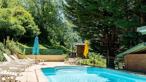 A swimming pool with lounge chairs and umbrellas, surrounded by trees. - Holiday Home 'Les Trois Maisons - Gite Vert' with Mountain View, Shared Pool and Wi-Fi (Osse-en-Aspe)