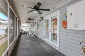 A covered porch with ceiling fans, a rocking chair, and a sign that says "SUMMER". - 629 Lakewood Circle- Sleeps 10 (MYRTLE BEACH)