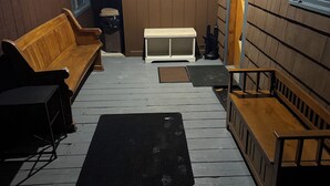 Een houten interieur met een bankje, een kleine tafel en een bank met rugleuning.