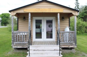 A small wooden cabin with a porch, a sign above the door, and a white door. - Spacious 4BR Northern Maine Retreat – On Trails with Game Room & Garage (Portage Lake)
