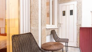 A room with a stone wall, a white door, and two wicker chairs. - Myo Design House: São Bento (Porto)