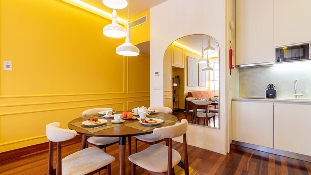 A dining area with a round table, chairs, and a breakfast setting. There is a kitchen area with a sink and cabinets. - Myo Design House: São Bento (Porto)