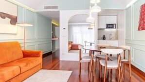 Een moderne woonkamer met een bank, eettafel, stoelen en een keuken op de achtergrond.