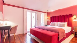 Een slaapkamer met een bed, een bureau, een stoel en een deur die leidt naar een buitenruimte.