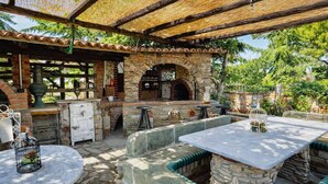 Une terrasse extérieure avec des sièges en pierre, un four en briques et un coin bar au style rustique.