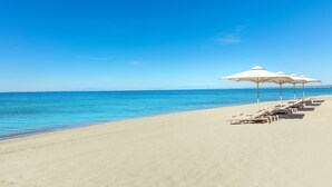 Une plage avec des parasols blancs et des chaises longues.