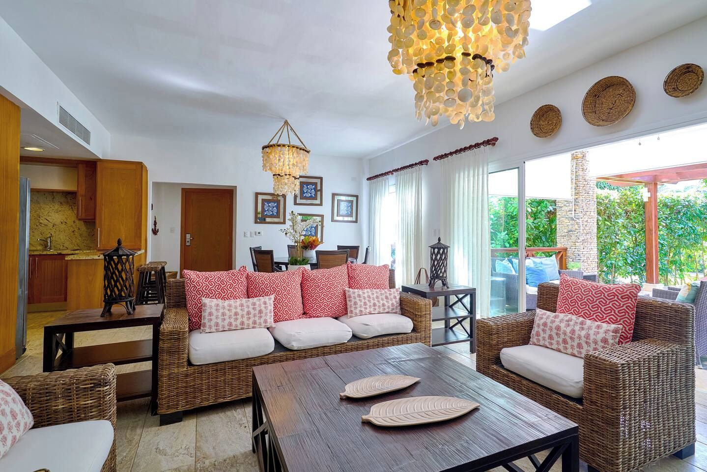A spacious living area with wicker furniture, a wooden coffee table, and a decorative chandelier.
