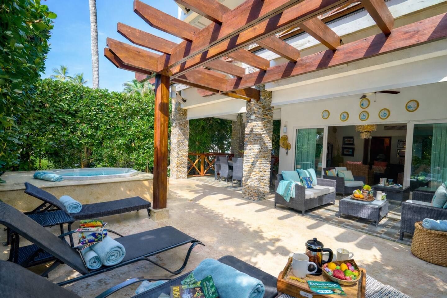 An outdoor patio with lounge chairs, a hot tub, and a dining area with wicker furniture.