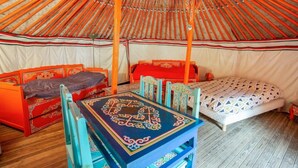 Interior de una yurtas tradicional con dos camas, una mesa y una silla.