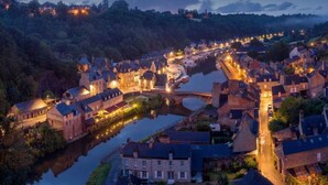 Un pueblo histórico con un río, edificios de piedra y un puente.