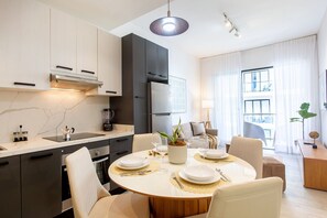 Eine moderne Küche mit Essbereich, ausgestattet mit einem runden Tisch für vier Personen, einem Einbauofen und einem großen Fenster für natürliches Licht.