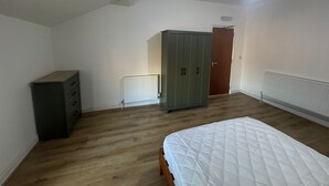 Un dormitorio con cama, armario, radiador y una puerta.