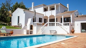 Een witte villa met een zwembad, een trap en een patio.